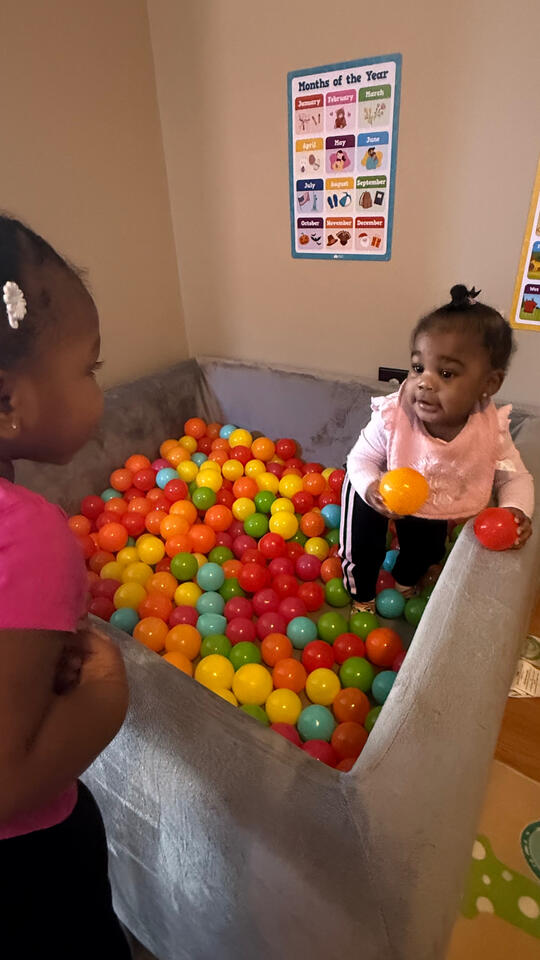 Play, Explore & Grow Young child enjoying supervised play in a colorful ball pit at Advanced Childcare Services LLC